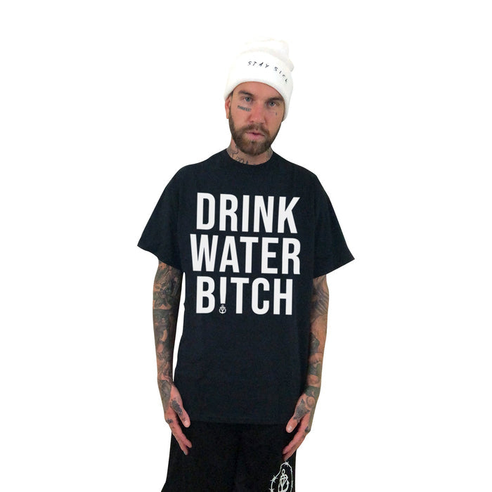 A tattooed man in a white beanie and Stay Sick Clothing’s bold black “DRINK WATER BITCH” tee stands against a white background, confidently promoting hydration with the brand’s unapologetic message.