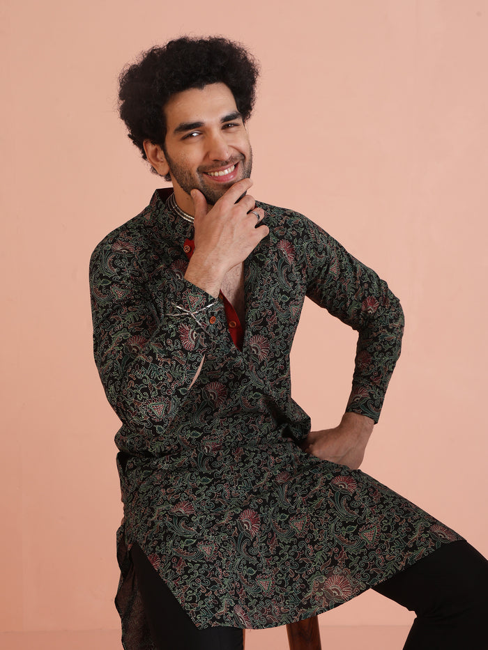 The model is seated comfortably on a chair, posing in Black Printed Cotton Silk Kurta Trouser Set of Kisah.