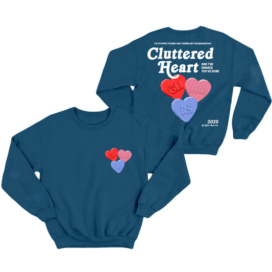 A blue glimmers sweatshirt featuring colorful candy hearts, Cluttered Heart on the back, and smaller front hearts labeled GL!, MME, and RS. Prominent white text and heart graphics complete the design.