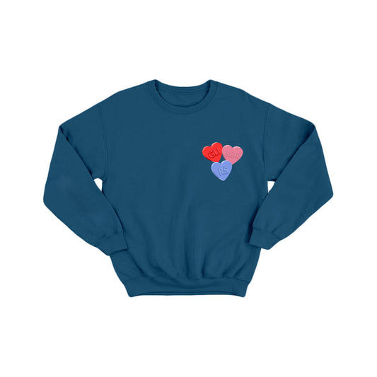 The glimmers blue crewneck sweatshirt features three candy hearts on the left chest—two red and one purple—with text styled like conversation heart candies.