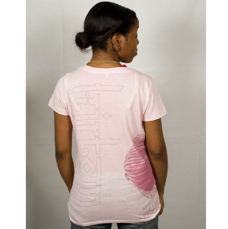 A woman with her hair tied back faces away, wearing a Mantralogy light pink t-shirt featuring bold vertical text and a red shell graphic on the back, set against a plain white background.