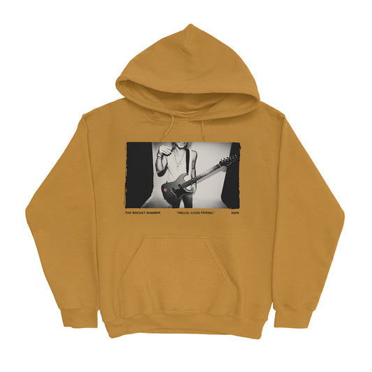 Mustard yellow fleece pullover hoodie by The Rocket Summer, showcasing a black-and-white photo of someone playing an electric guitar with “THE ROCKET SUMMER,” “HELLA GOOD FRIEND,” and “2023” printed below.