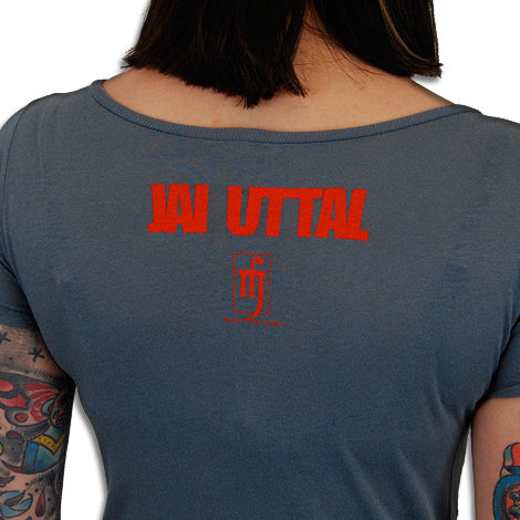 A person with tattooed arms is seen from behind wearing a blue Mantralogy shirt with “JAI UTTAL” printed in red on the back, along with a small red graphic and additional text below the name.