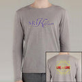 A person wears a light grey SRI Kirtan long-sleeve shirt featuring the brand name in stylized letters on the front and a yellow geometric design with LIVE your LOVE in bold red and yellow text on the back.