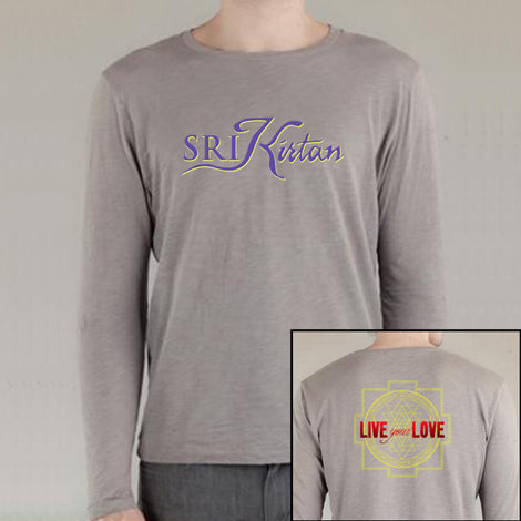 A person wears a light grey SRI Kirtan long-sleeve shirt featuring the brand name in stylized letters on the front and a yellow geometric design with LIVE your LOVE in bold red and yellow text on the back.