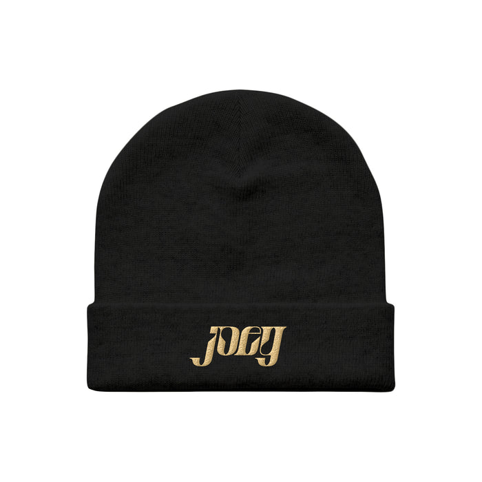 A black beanie hat by Joey Fleming featuring joey embroidered in gold lettering on the front fold.