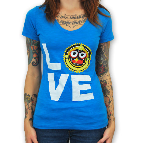 A tattooed woman wears a blue Mantralogy T-shirt with LOVE on it, where the O is replaced by a vibrant graphic of Lord Jagannaths face.