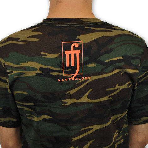 A person wears a Mantralogy camouflage t-shirt in green and brown, featuring an orange Mantralogy logo and stylized symbol on the back. Only the back and shoulders are visible against a white background.