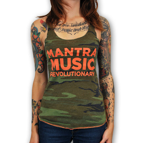 A woman with colorful tattoos on her arms and chest wears a camouflage tank top featuring bold orange MANTRA MUSIC REVOLUTIONARY text by Mantralogy. The image is cropped at her neck and waist.