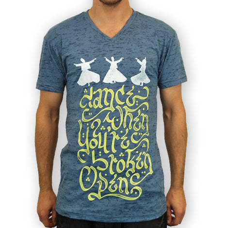 A person wearing a blue Mantralogy V-neck T-shirt with three white whirling dervishes above the phrase “dance when you’re broken open” in decorative yellow script.