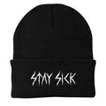 A black winter beanie from Stay Sick Clothing, featuring STAY SICK embroidered in jagged white letters on the cuff—a bold, metal-inspired accessory for your look.