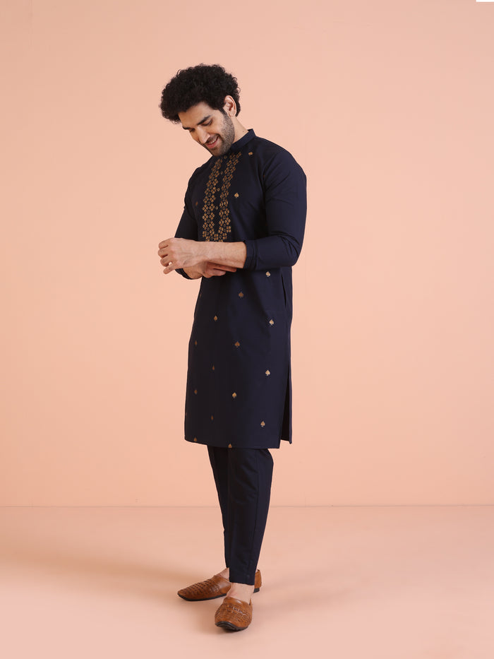 The model is looking down while wearing Kisah Men’s Navy Blue Embroidered Kurta Set, adjusting the kurta softly