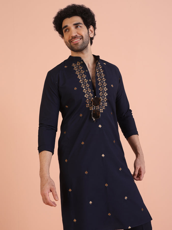 The model is leaning slightly, flaunting Kisah Men’s Navy Blue Embroidered Kurta Set with embroidered front detailing