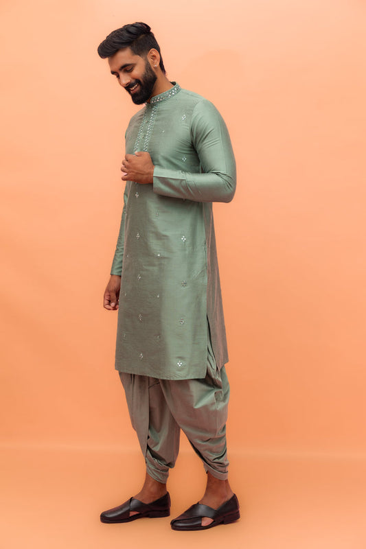 The side view shows the model , walking in Kisah Sage Green Mirror Work Kurta with Dhoti with loafers