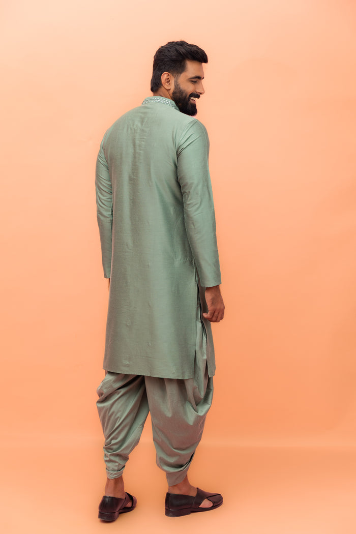 The back view shows the model , flaunting Kisah Sage Green Mirror Work Kurta with Dhoti set neatly