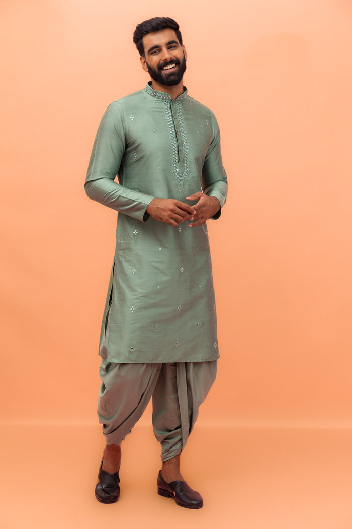 The model is standing confidently  wearing Kisah Sage Green Mirror Work Kurta with Dhoti set gracefully