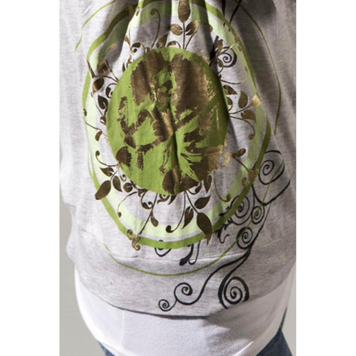 A gray Mantralogy Shantala T-shirt features a circular green and gold floral design with swirling black lines, inspired by Saraswati, Goddess of art and music, shown layered over a white top.