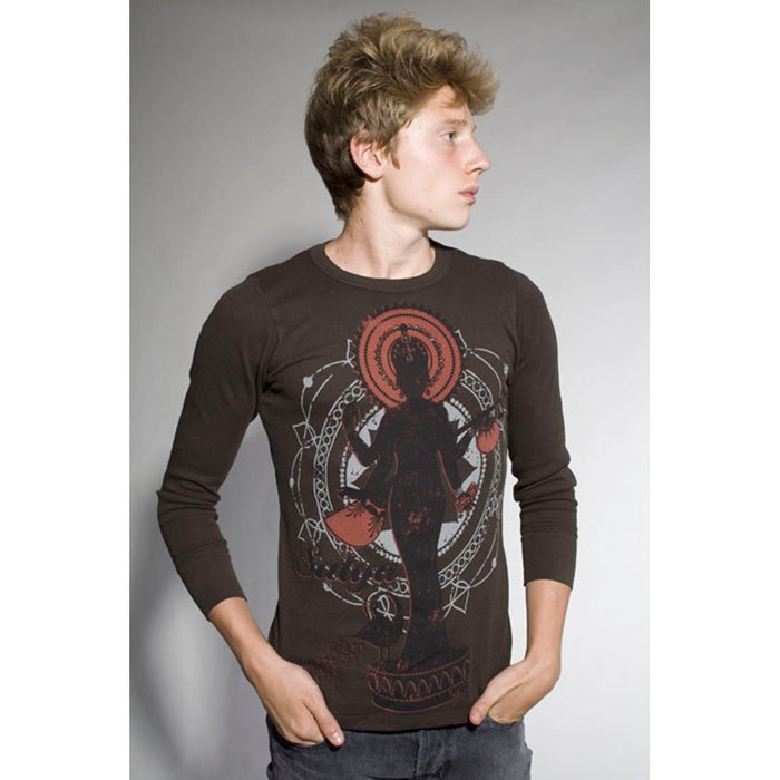 A young man with light brown hair wears a Mantralogy dark long-sleeve shirt featuring a bold red and black deity graphic, stands with hands in pockets, and looks to his left against a plain background.