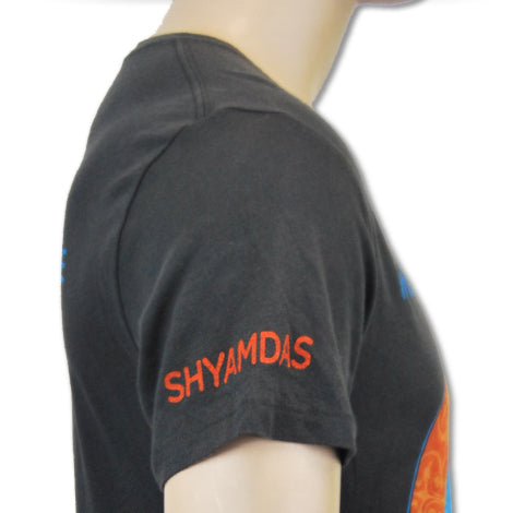 A close-up side view of a person wearing a black Mantralogy T-shirt with SHYAMDAS embroidered in red on the sleeve.
