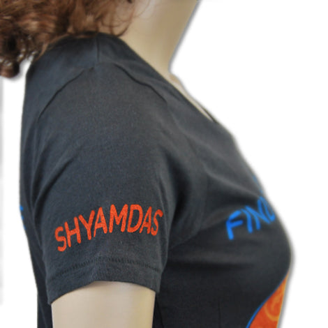 A close-up side view of a person wearing a black Mantralogy T-shirt with SHYAMDAS embroidered in red letters on the sleeve.
