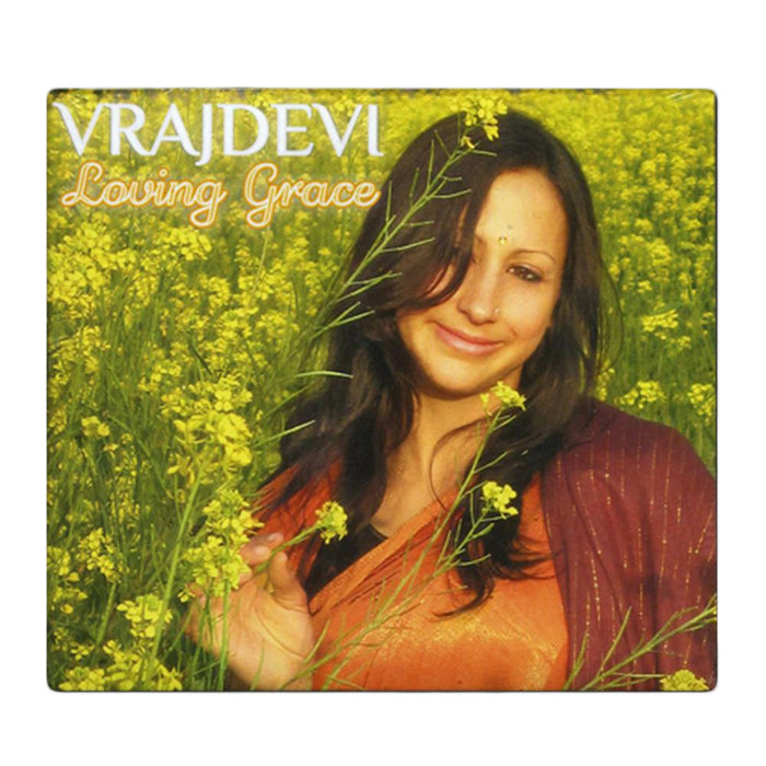 A woman in a maroon shawl stands amid yellow flowers, smiling softly at the camera. The text reads Vrajdevl Loving Grace, inspired by the devotion of Radhe Krishna.