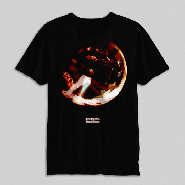 A black Boundaries Comfort Colors T-shirt featuring an abstract circular design with red and orange tones, blurred human figures, UNBEATEN text, smaller text below, and made from garment-dyed fabric.